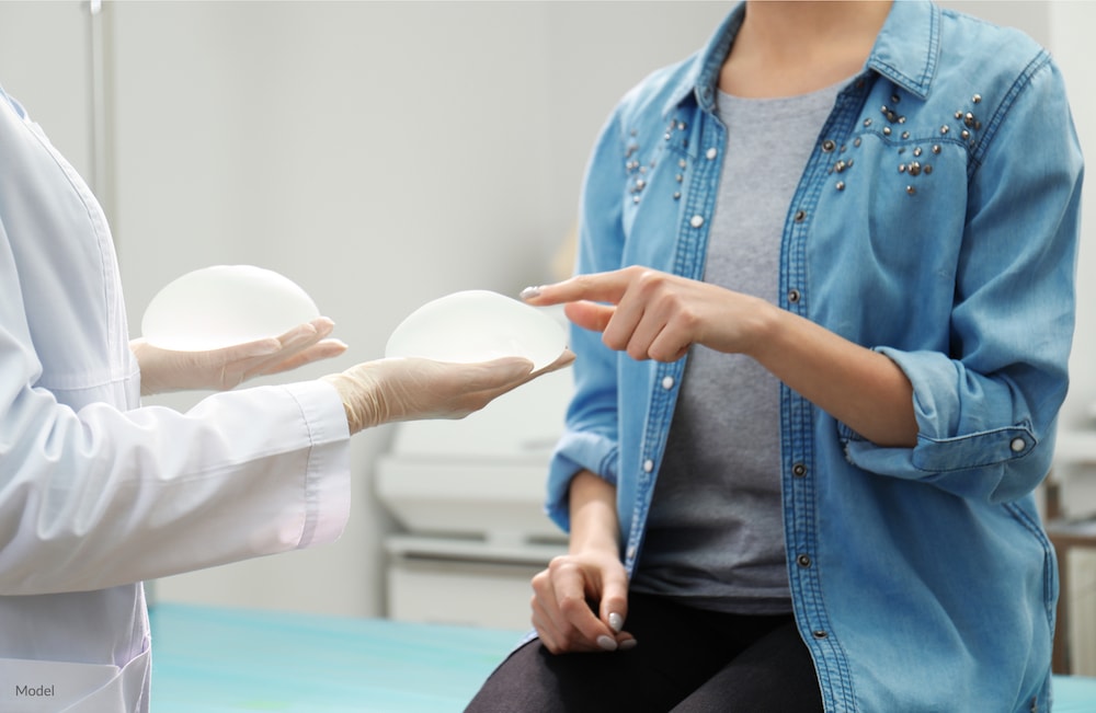 Woman touching a breast implant during her breast augmentation consultation.