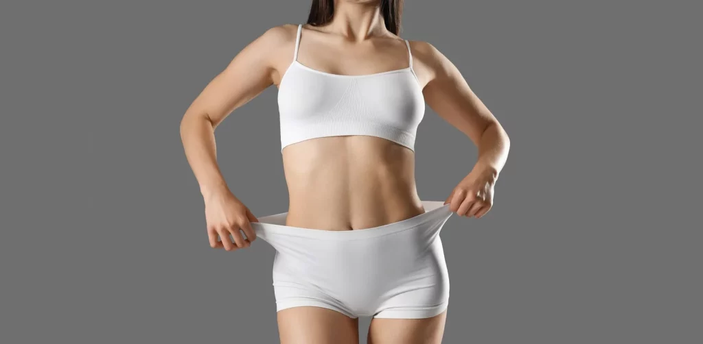 Woman with a flat, toned abdomen showing extended tummy tuck body contouring results